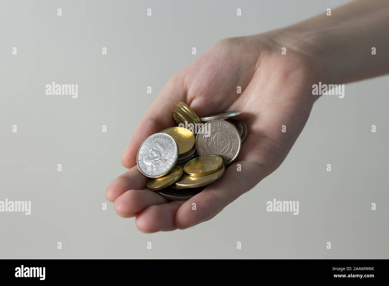 Hand holding giving Philippines peso coins paying bills, payment procedure or bribe, salary, poverty Stock Photo