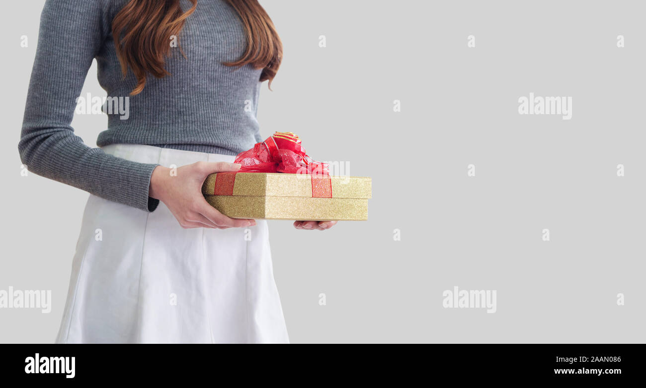 Young woman holding gift box, on gray background Stock Photo