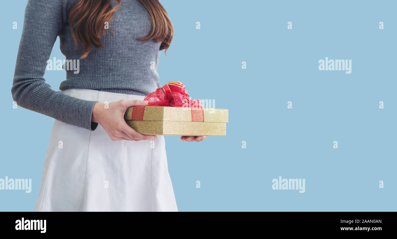 Woman holding gift box, isolated on blue background Stock Photo