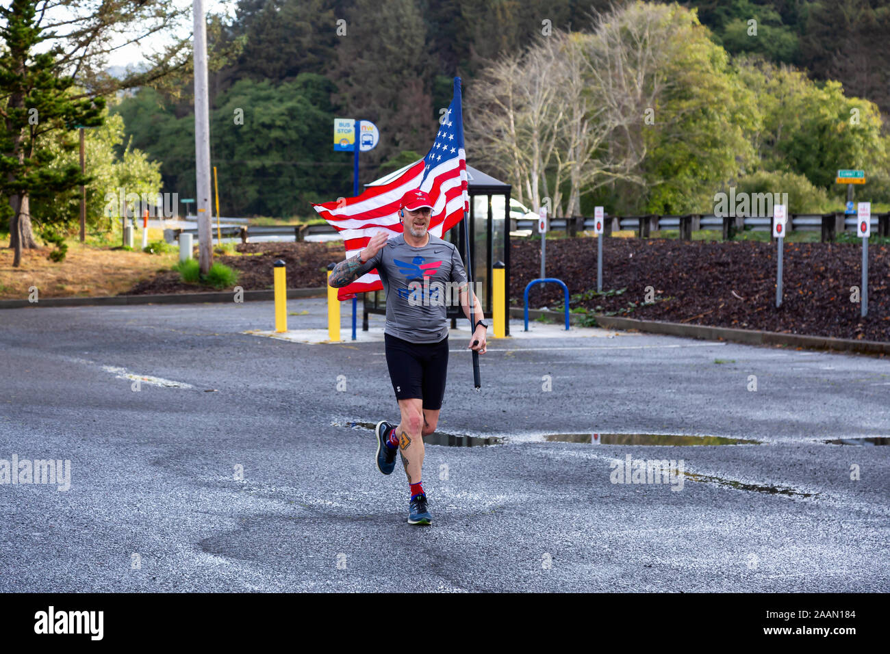 Neskowin, Oregon, United States - September 8, 2019: Proud member of Team RWB is running outside with an American Flag during a summer morning. Stock Photo