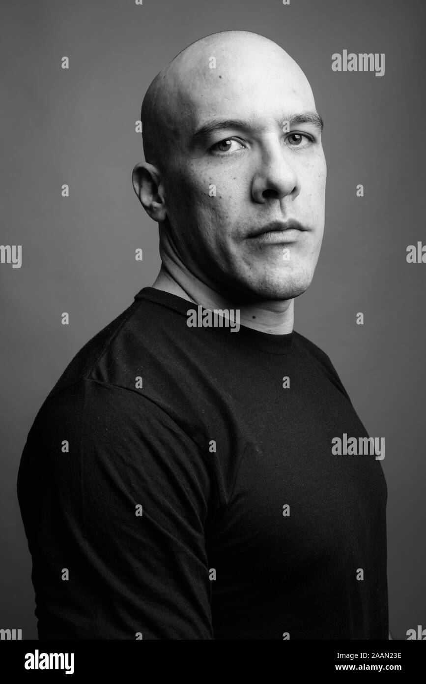 Handsome bald man against gray background in black and white Stock Photo