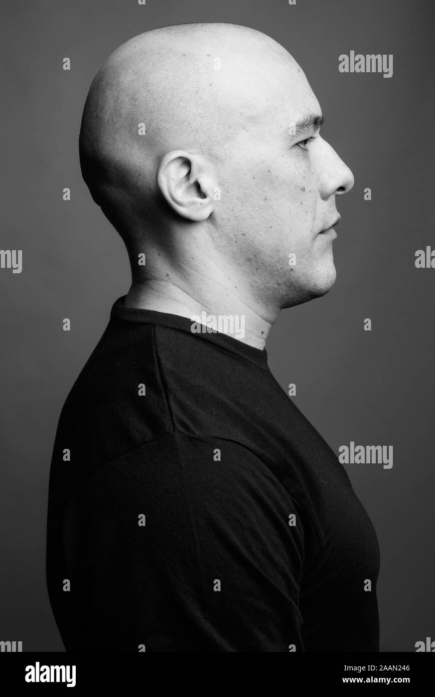 Handsome bald man against gray background in black and white Stock ...