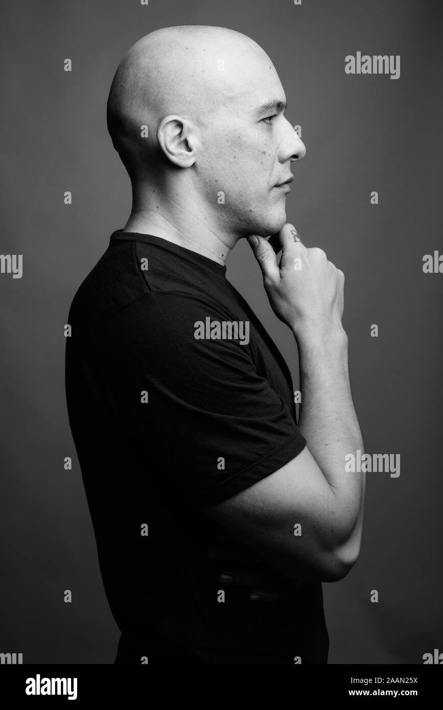 Handsome bald man against gray background in black and white Stock ...