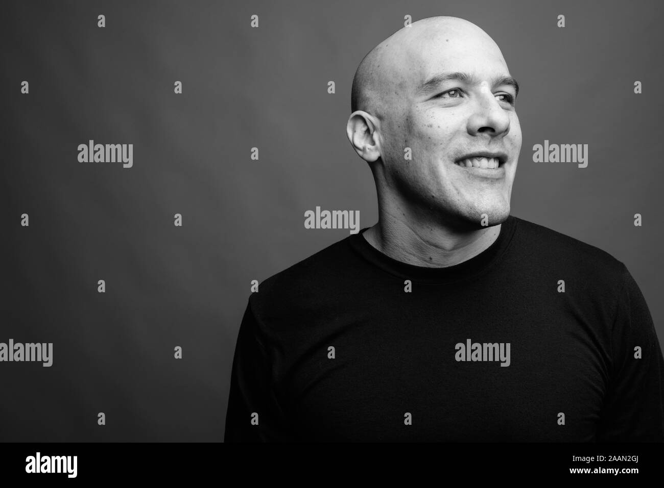 Handsome bald man against gray background in black and white Stock ...