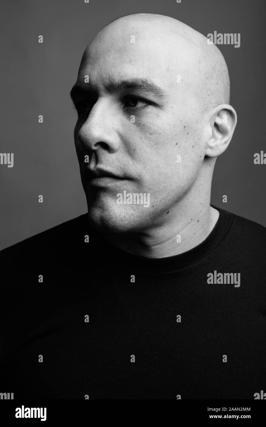 Handsome bald man against gray background in black and white Stock Photo