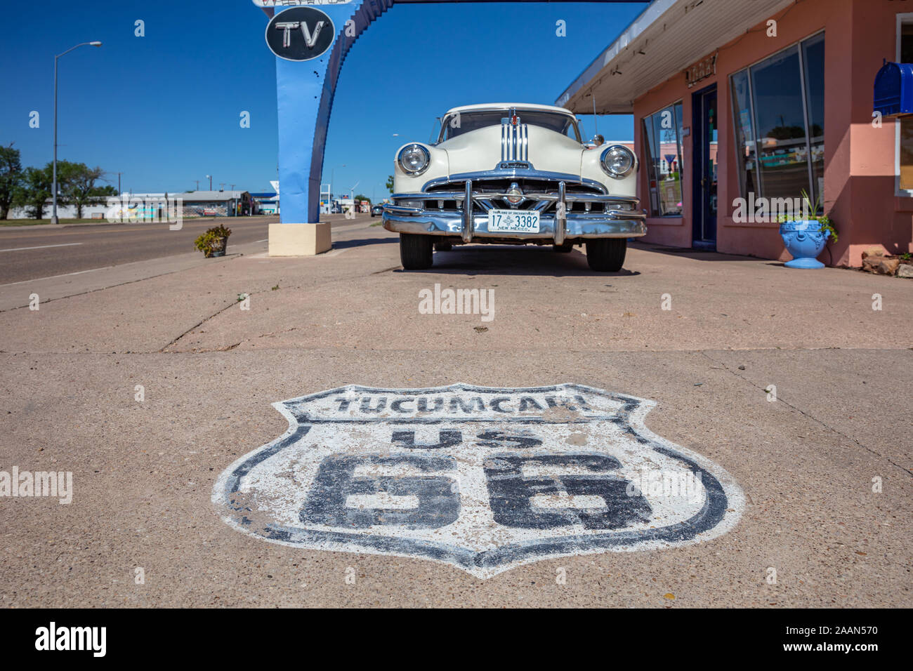 Tucumcari, New Mexico, USA. May 14, 2019. Worn out stamp of mother road, route 66, on the pavement. An antique pontiac car is parked at the entrance o Stock Photo