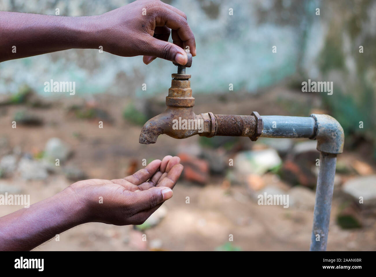 water crisis is a serious threat to India and worldwide,a man holding his hand under the tap for water. Stock Photo