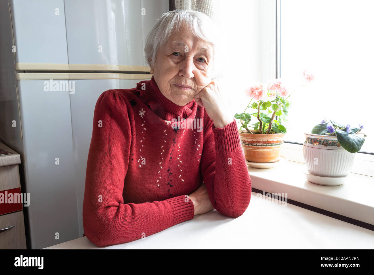 Elderly lonely woman depressed sitting at the table Stock Photo