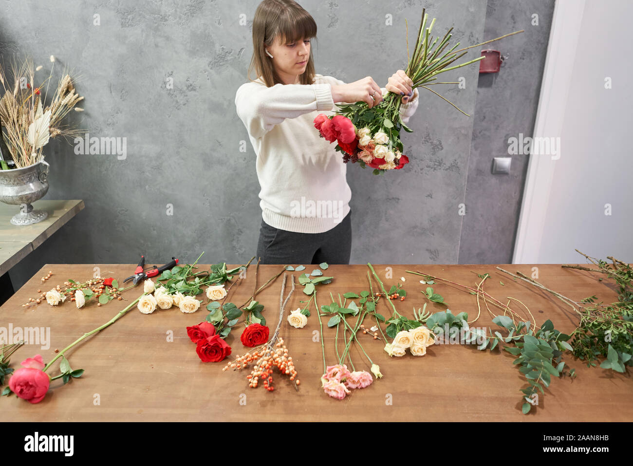 European floral shop concept. Florist woman creates red beautiful bouquet of mixed flowers. Handsome fresh bunch. Education, master class and Stock Photo