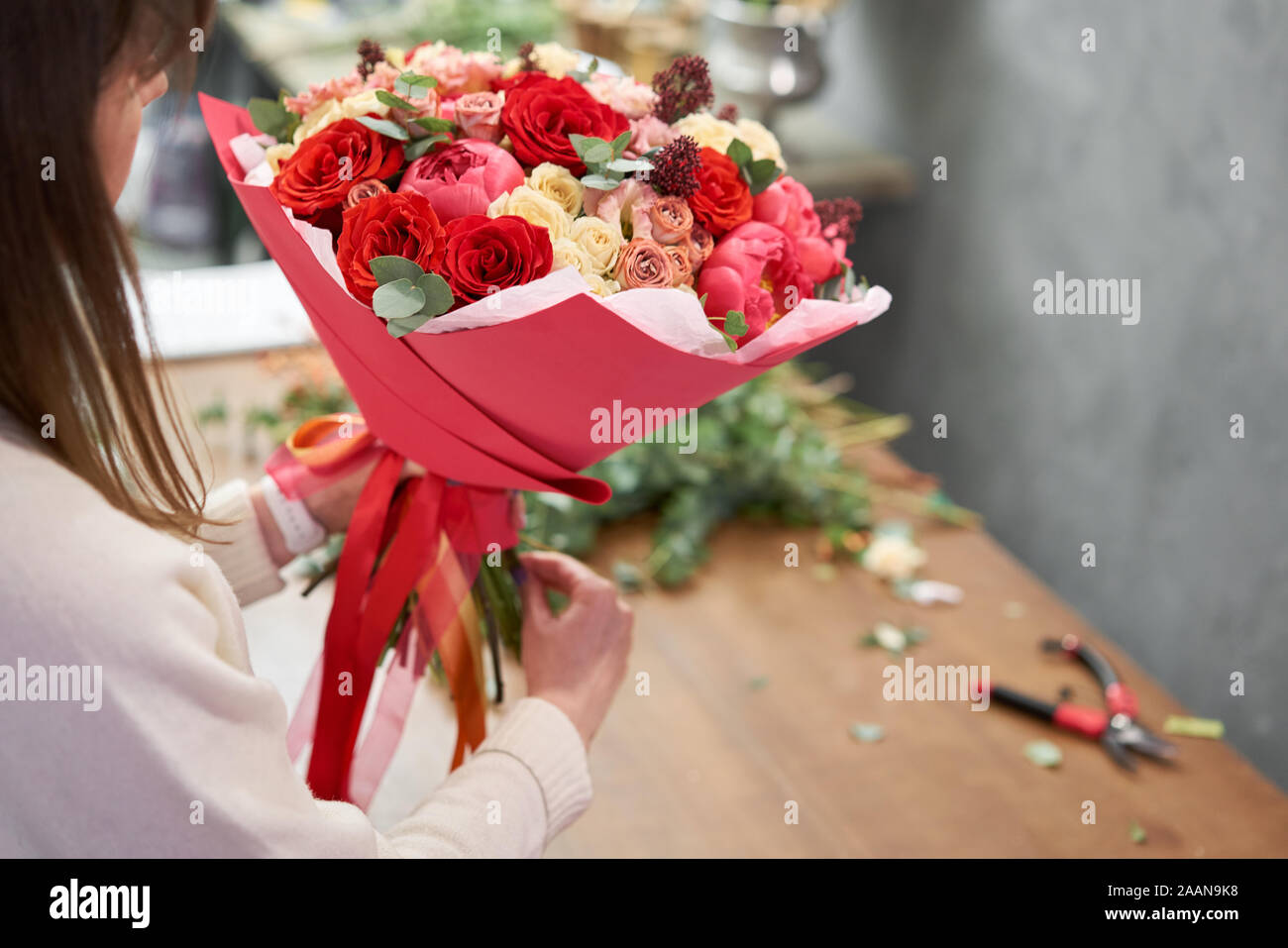 Step by step florist woman creates red beautiful bouquet of mixed flowers. Handsome fresh bunch. Education, master class and floristry courses Stock Photo