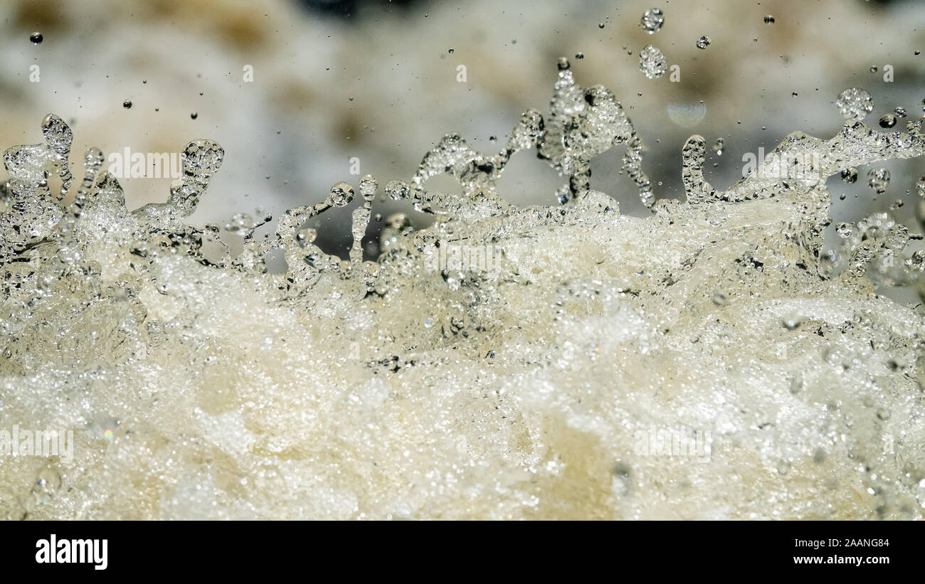 Water backgrounds with foam spray fast flow. The water in mad flows with droplets and whirlpools