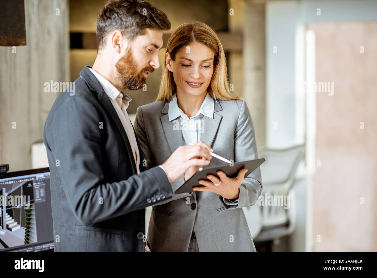 Two strictly dressed office employees working with digital tablet in the office Stock Photo