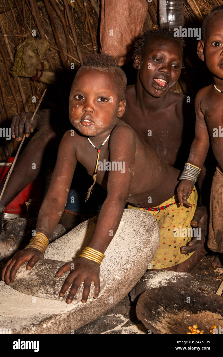Ethiopia, South Omo, Jinka, Mago National Park, Mursi village, young child grinding sorghum inside hut Stock Photo