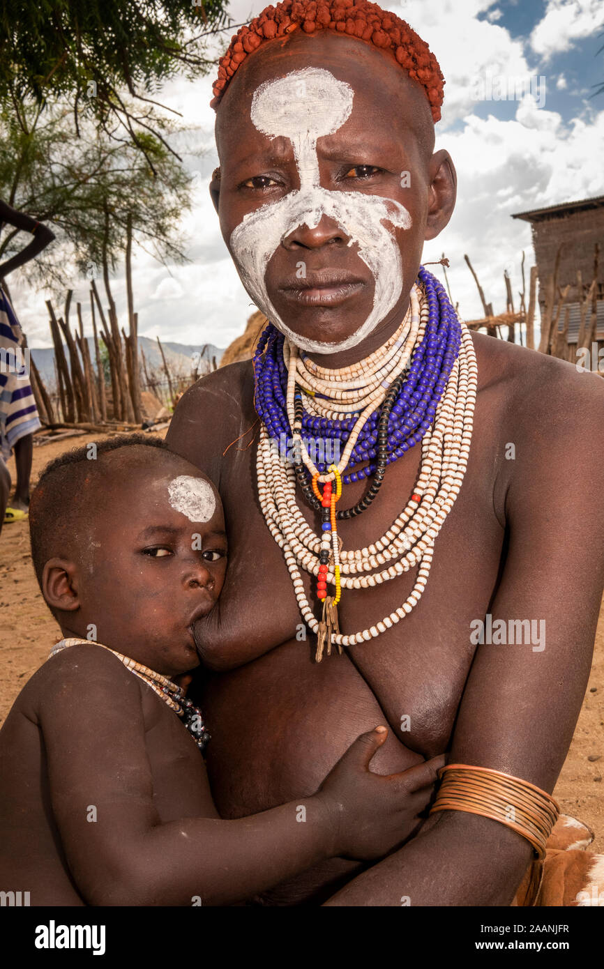 Ethiopia, South Omo, Kolcho village, traditionally dressed Karo tribal woman breastfeeding young child Stock Photo