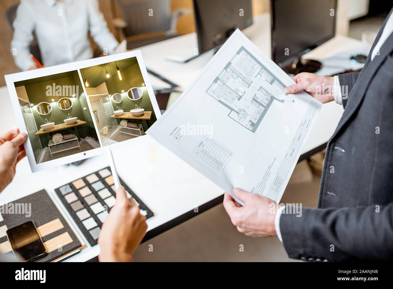 Creative office employees working on some architectural project, holding plans and interior renderings, close-up on the blueprints Stock Photo