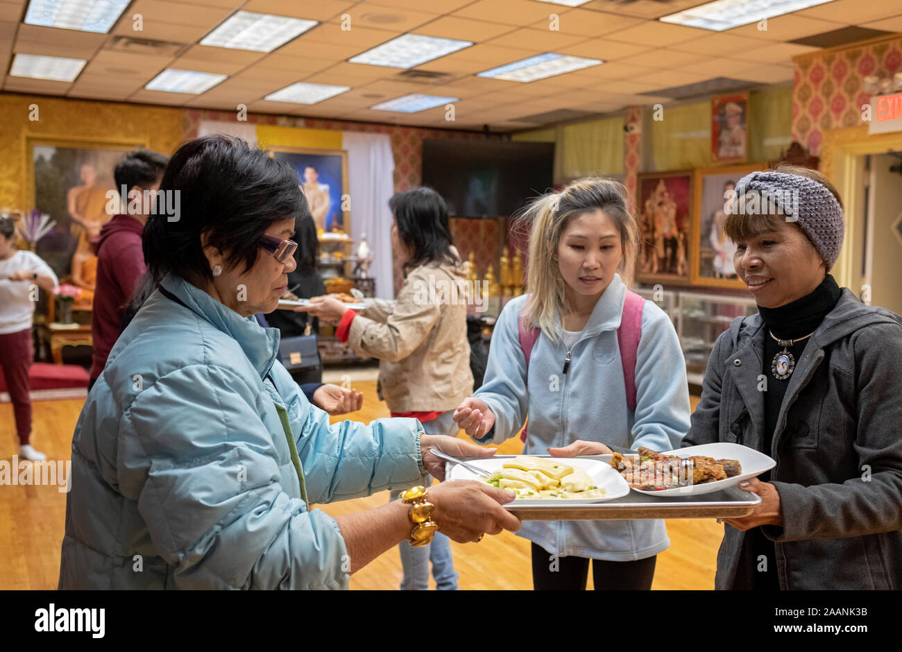 Thai women and a man pass food to one another to feed their monks