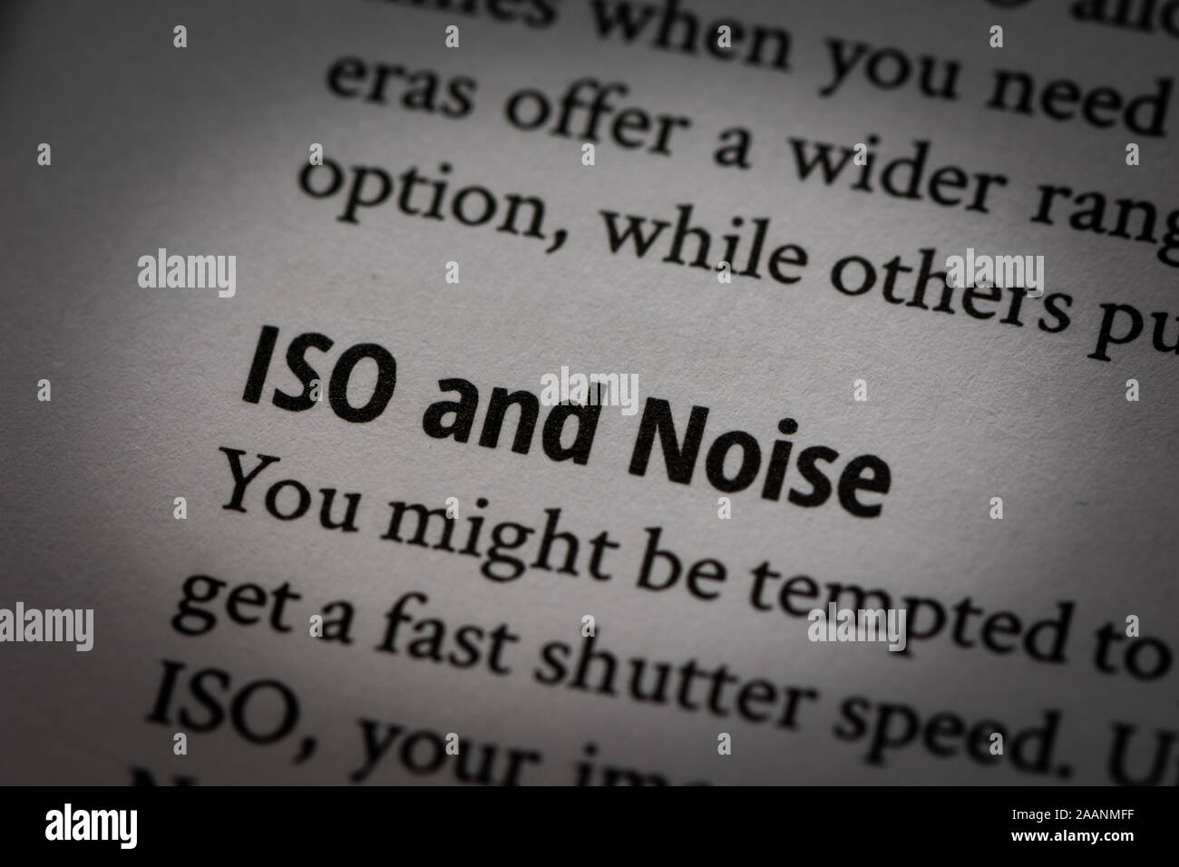 Macro photograph of words 'ISO and Noise' in white page of a book about photography with small vignette applied. Stock Photo