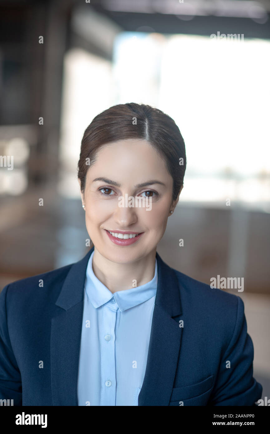 Beautiful business lady wearing dark jacket smiling while feeling motivated Stock Photo