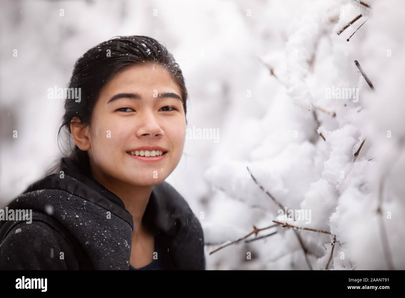 Biracial teen girl or young woman outdoors in winter enjoying fresh snow fall Stock Photo