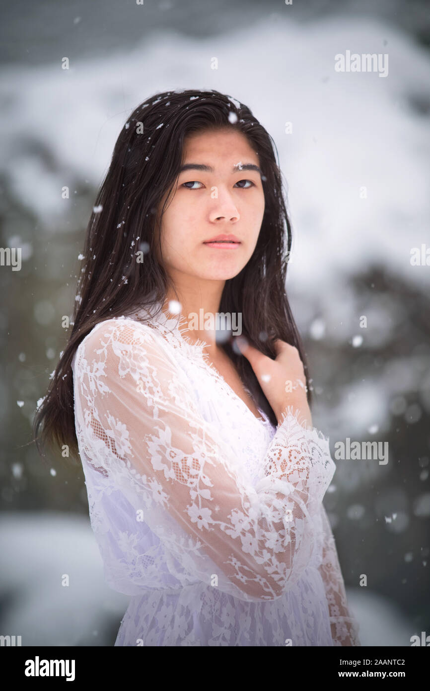 Biracial teen girl or young woman outdoors in winter enjoying fresh snow fall Stock Photo