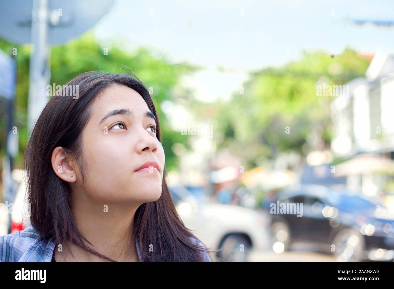 Biracial teen girl or young woman tourist looking up, profile,  on the streets of Phnom Pehn, Cambodia Stock Photo