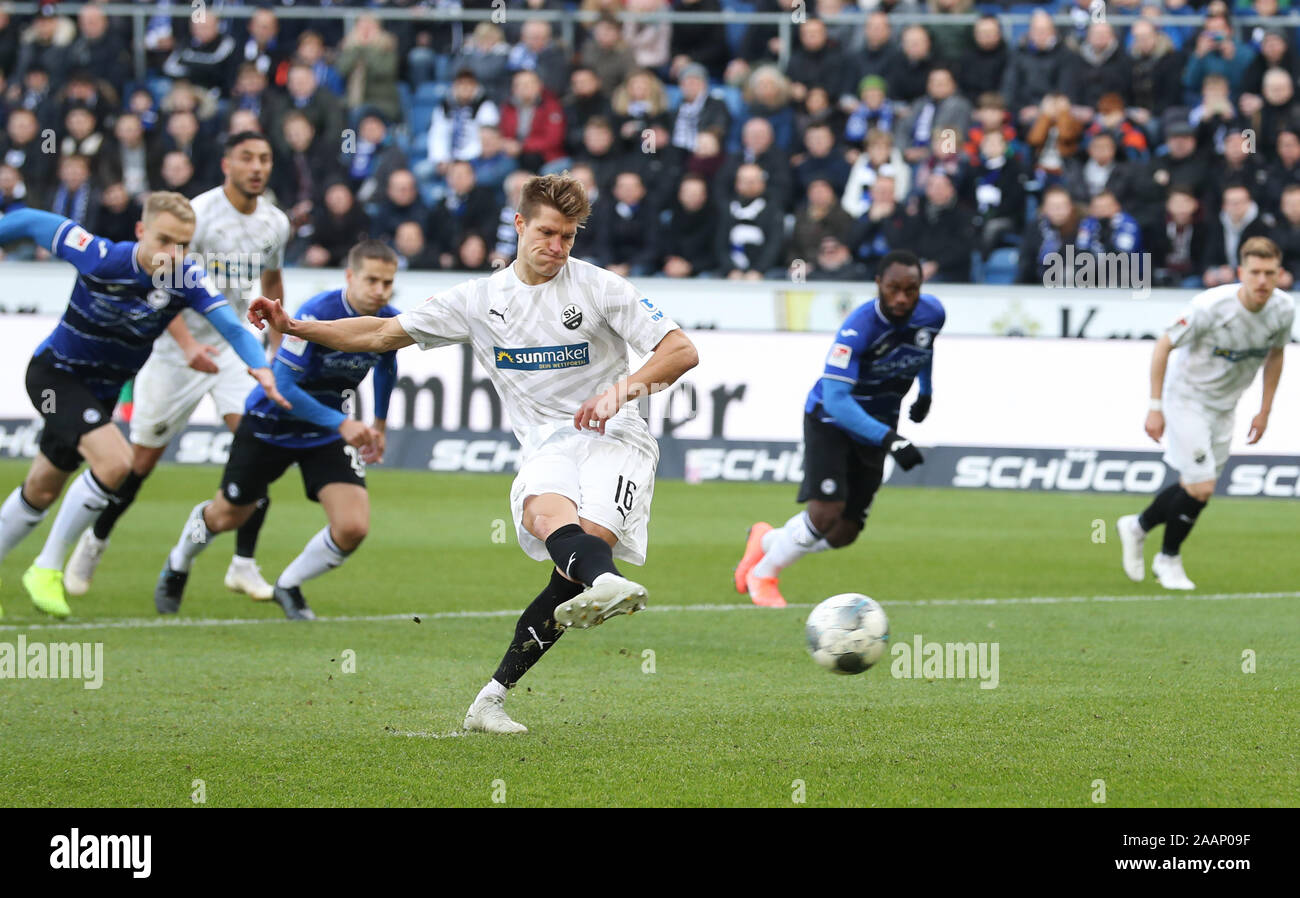 23 November 2019, North Rhine-Westphalia, Bielefeld: Soccer: 2nd Bundesliga, Arminia Bielefeld - SV Sandhausen, 14th matchday in the Schüco Arena. Kevin Behrens (M) from Sandhausen shoots a penalty kick, which is held by Bielefeld's goalkeeper Ortega (not in the picture). Photo: Friso Gentsch/dpa - IMPORTANT NOTE: In accordance with the requirements of the DFL Deutsche Fußball Liga or the DFB Deutscher Fußball-Bund, it is prohibited to use or have used photographs taken in the stadium and/or the match in the form of sequence images and/or video-like photo sequences. Stock Photo