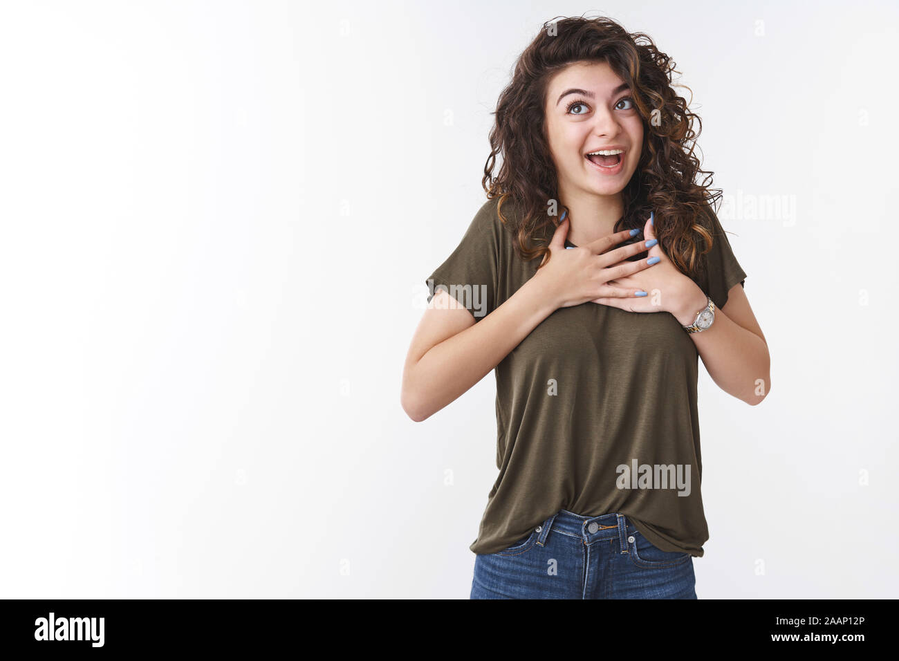 Happy pleased charming friendly girl retelling touching story press palms chest grateful thrilled smiling look up excited have lucky day grateful god Stock Photo