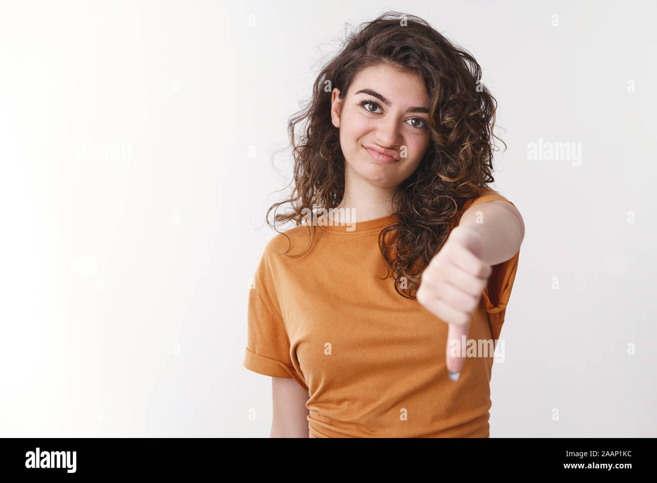 Lame. Unimpressed disappointed attractive charismatic curly-haired girl frowning cringing dislike show thumb-down gesture mocking losing team, give Stock Photo