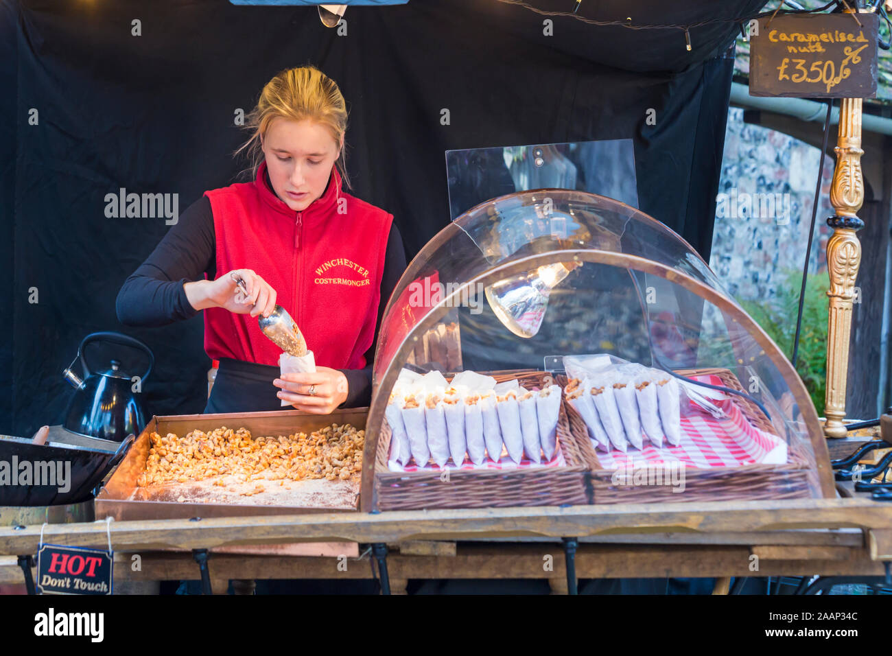 Winchester Costermonger bagging up caramelised nuts at Winchester Christmas Market, Hampshire, UK in December Stock Photo