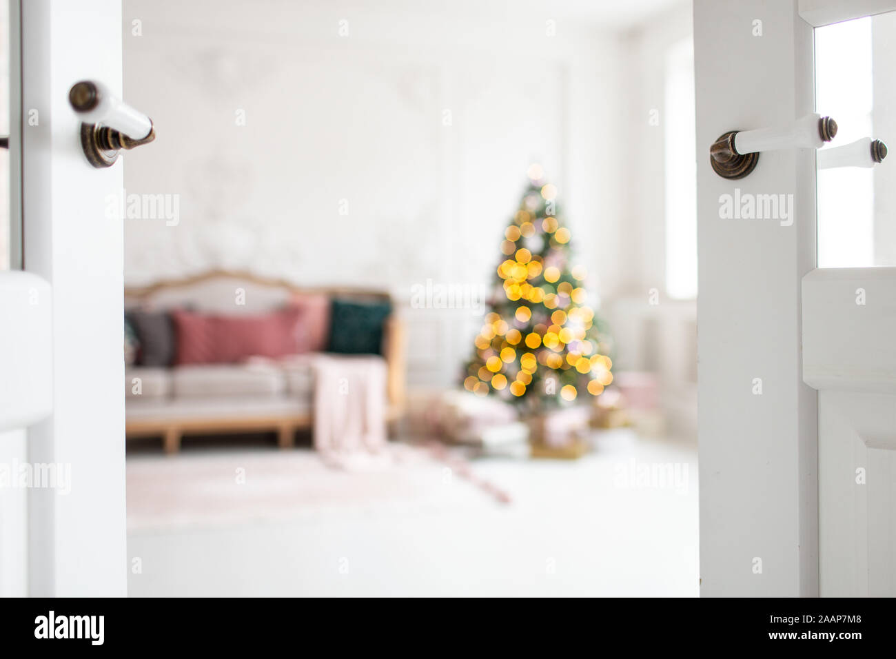 White sofa standing next to christmas tree surrounded by gift boxes. Selective focus. Stock Photo