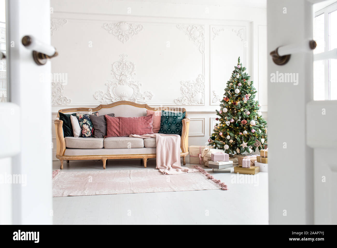 White sofa standing next to christmas tree surrounded by gift boxes. Selective focus. Stock Photo