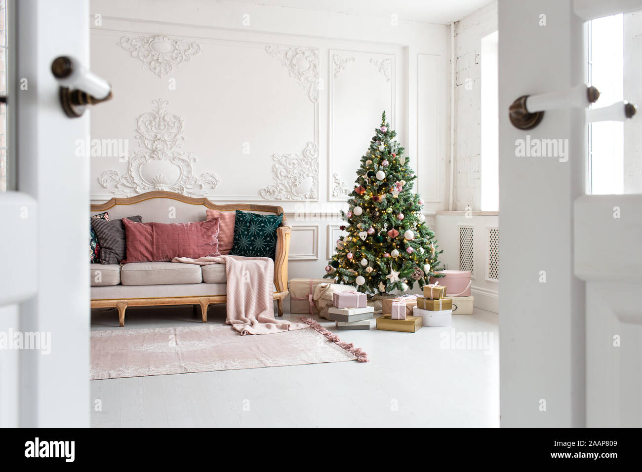 White sofa standing next to christmas tree surrounded by gift boxes. Selective focus. Stock Photo