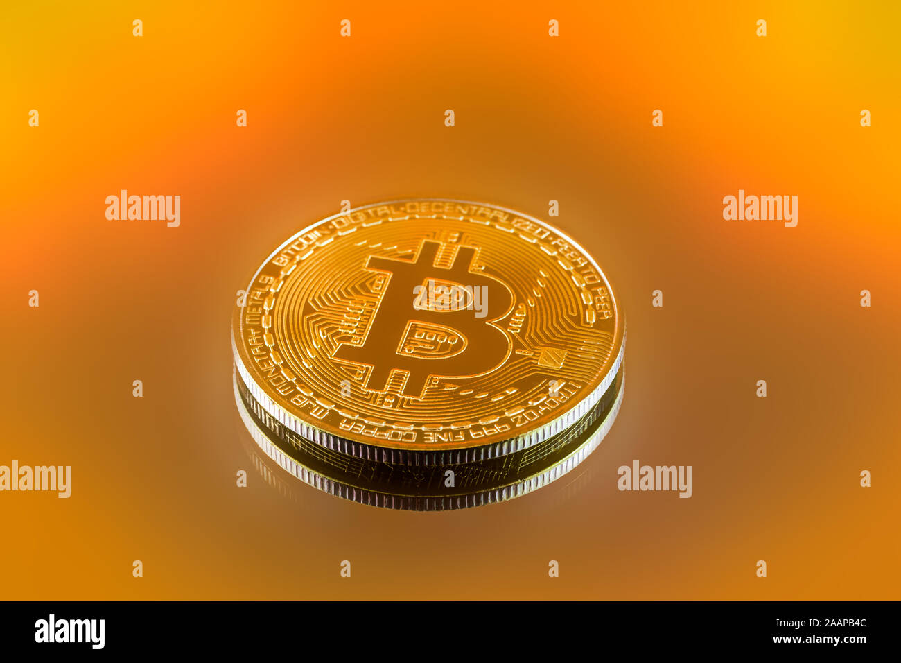 Gold color physical Bitcoin crypto currency in bright light with yellow brown background Stock Photo