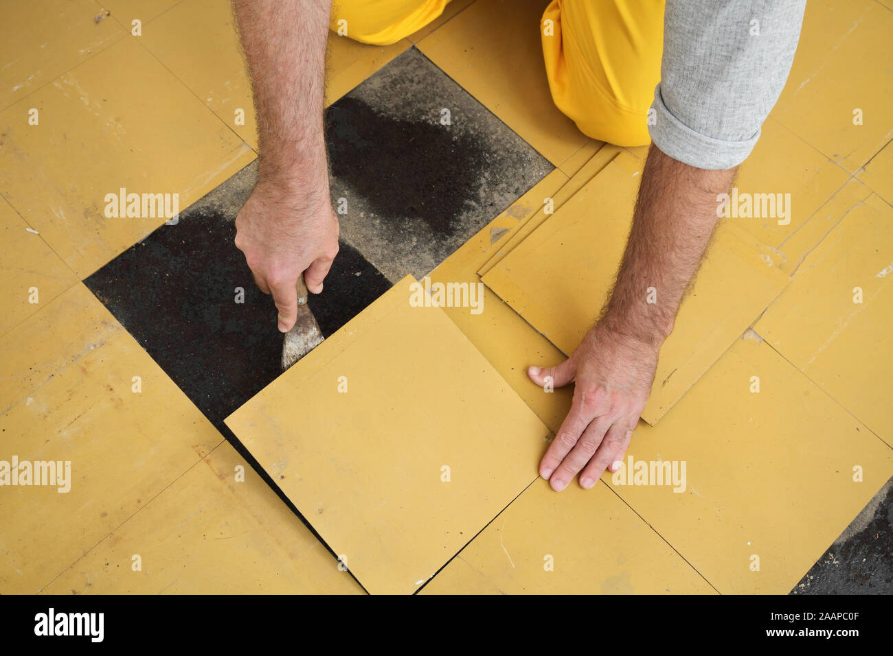 Worker Removing Old Vinyl Tiles From Kitchen Floor Using Spatula
