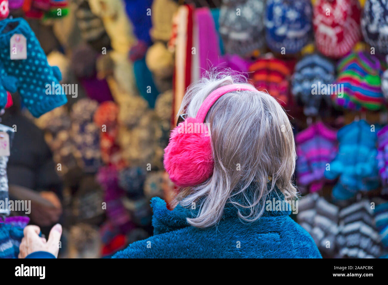 Woman wearing ear muffs looking at hats on market stall at Winchester