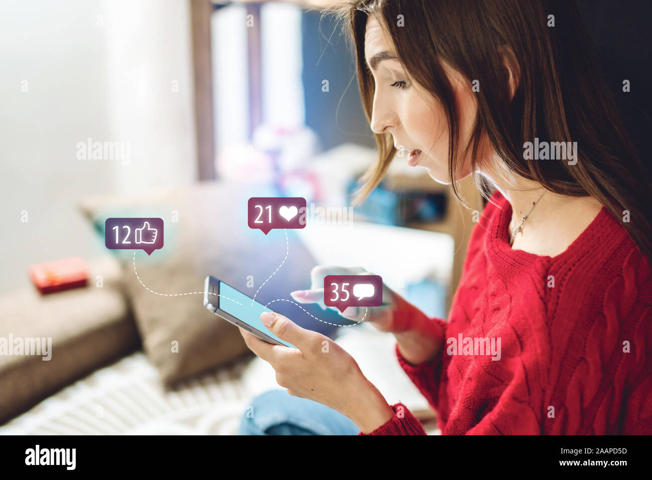 Young beautiful woman using her phone spends time on social looking at the display. Girl is reading the comments to the post and enjoying the likes on Stock Photo