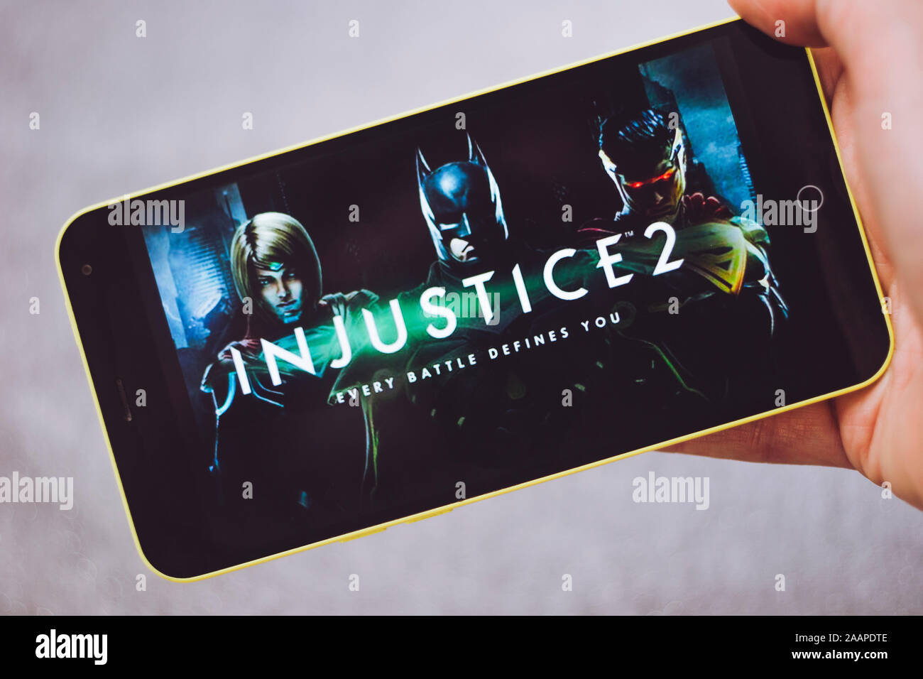 Berdyansk, Ukraine - March 4, 2019: Hands holding a smartphone with Injustice 2 game on display screen. Stock Photo