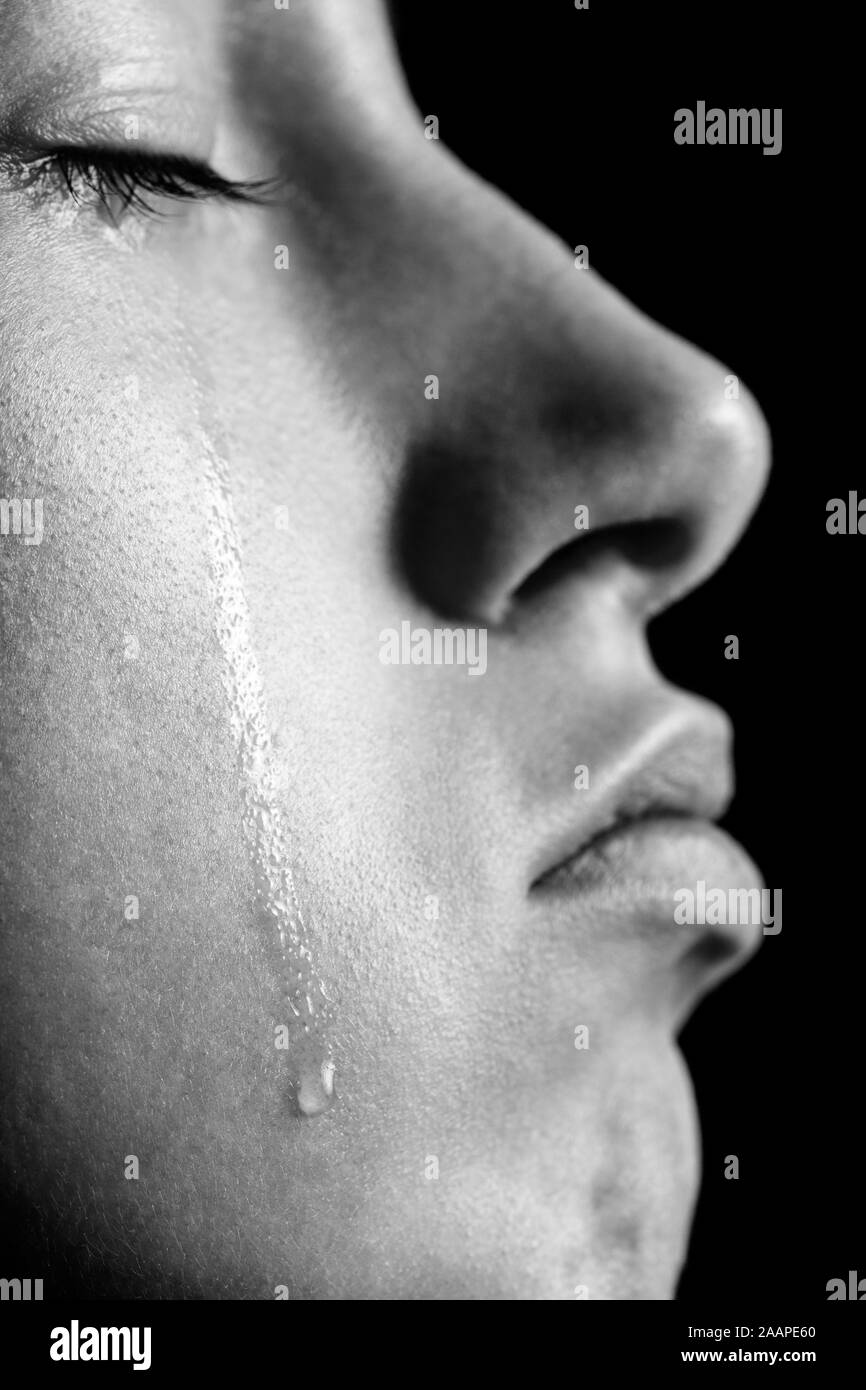 sad woman with closed eyes crying, on black background, closeup portrait, profile view, monochrome Stock Photo