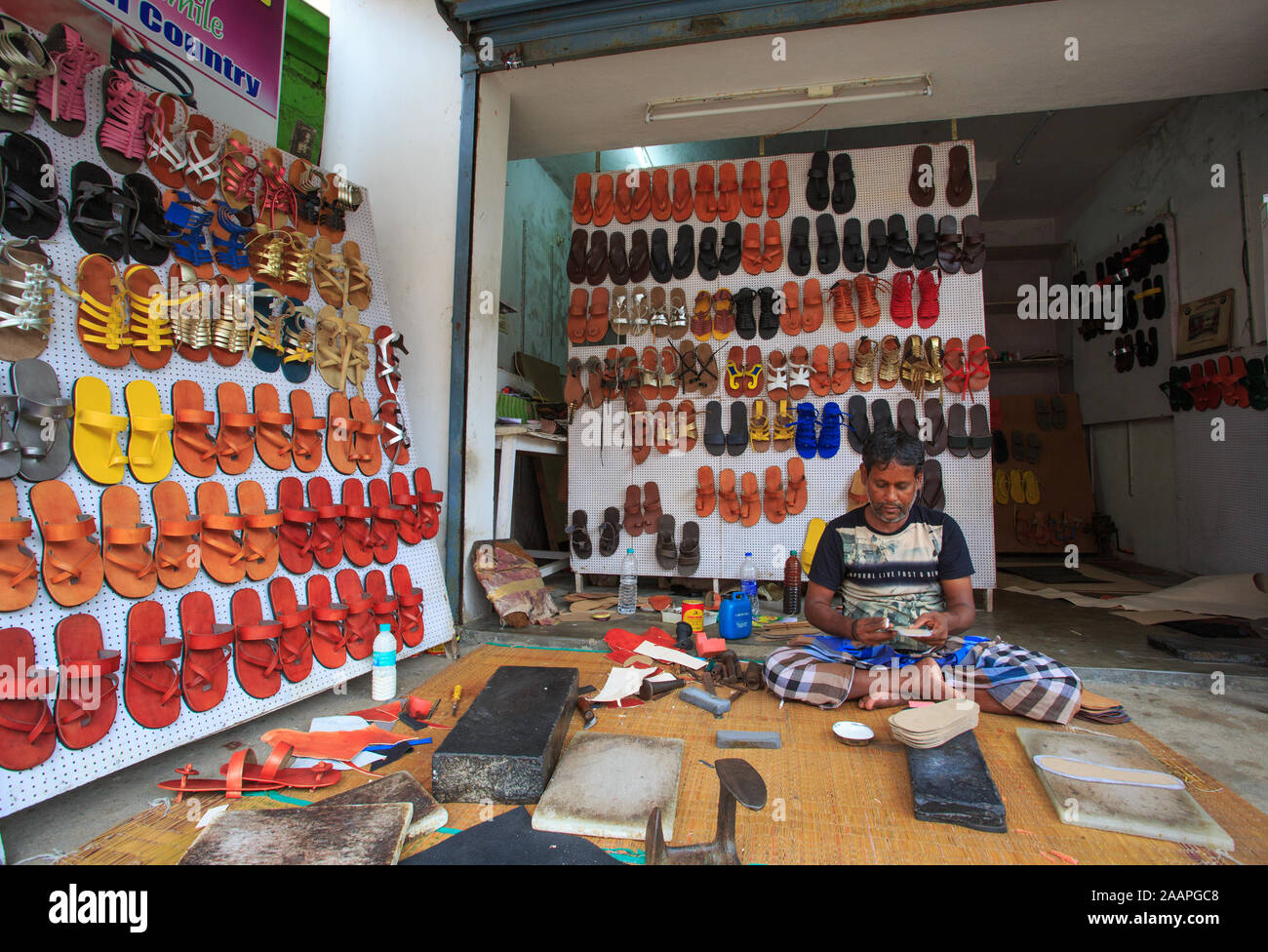 A Shoe Maker making the shoes at a roadside shop in Mahabalipuram (India Stock Photo