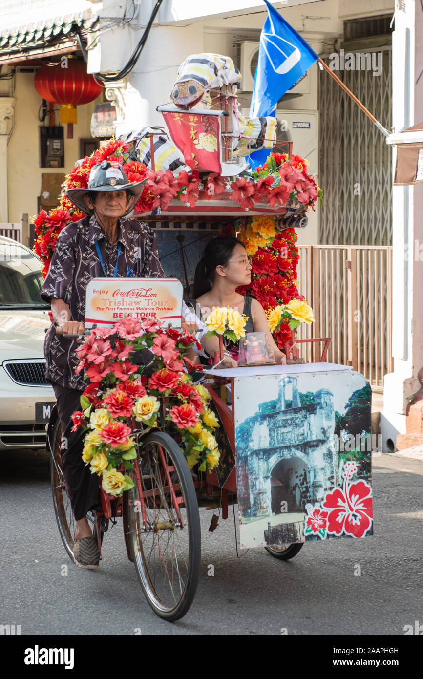 Tourists taking a ride in a decorated trishaw in Malacca, Malaysia Stock Photo