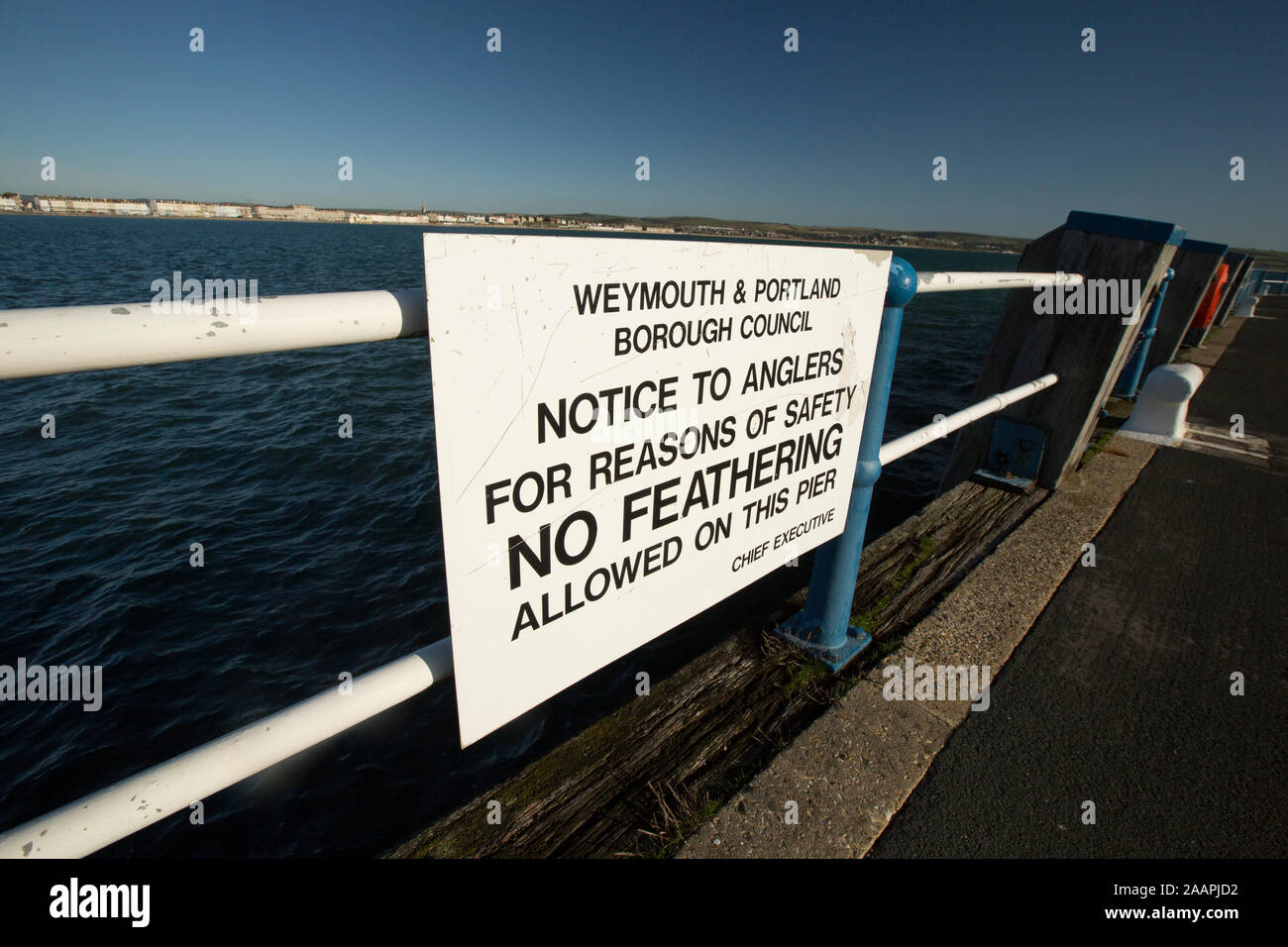 A sign on Weymouth’s Pleasure Pier indicating that no feathering is allowed. Feathering is a method of fishing, generally for mackerel, that involves Stock Photo
