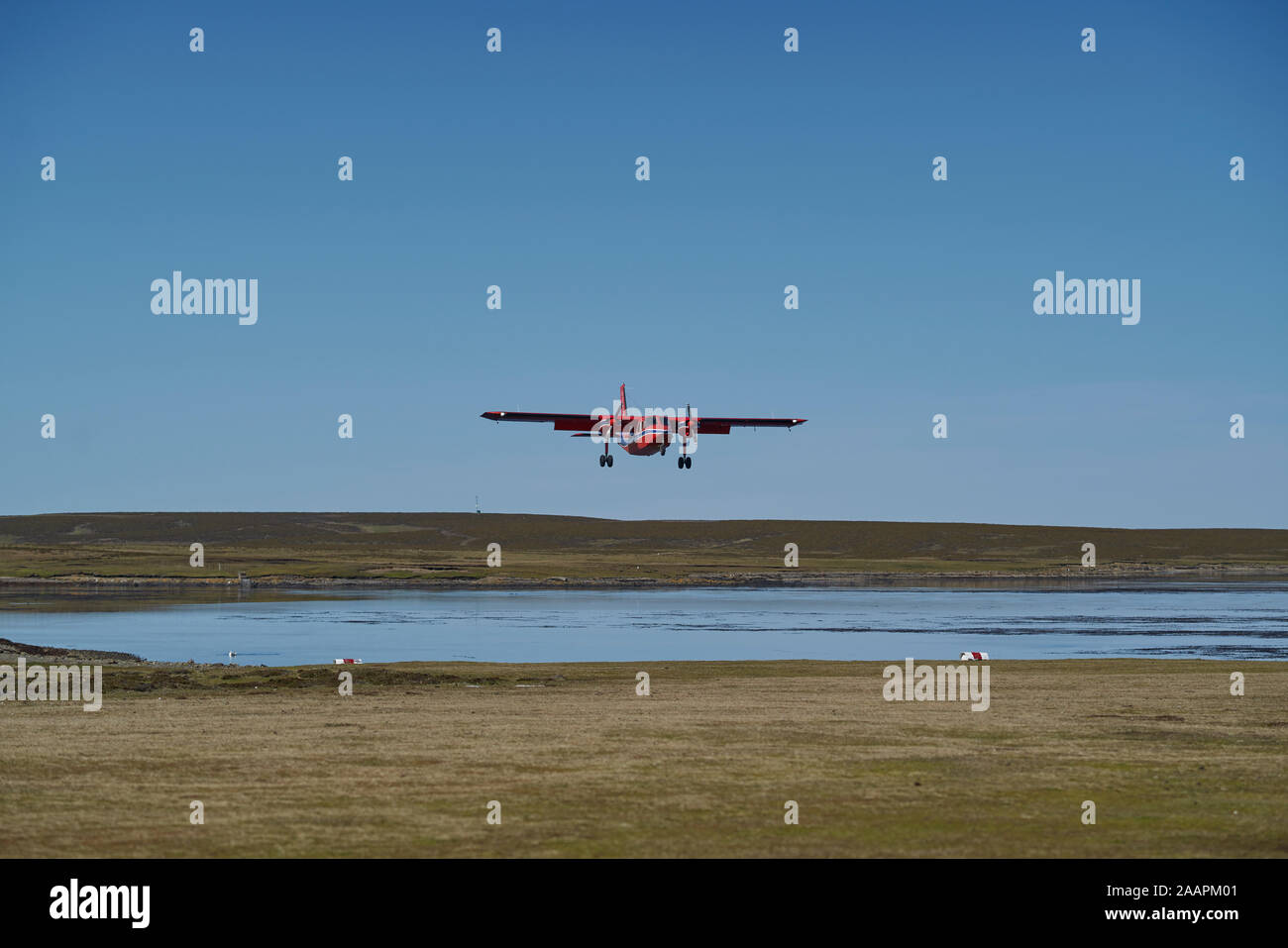 Small aircraft coming in to land on a grass airstrip on Bleaker Island in the Falkland Islands Stock Photo