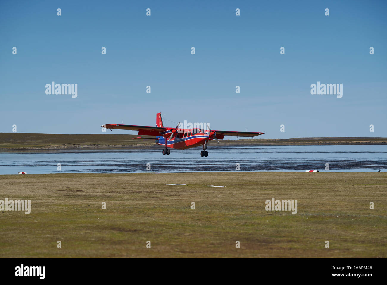 Small aircraft coming in to land on a grass airstrip on Bleaker Island in the Falkland Islands Stock Photo