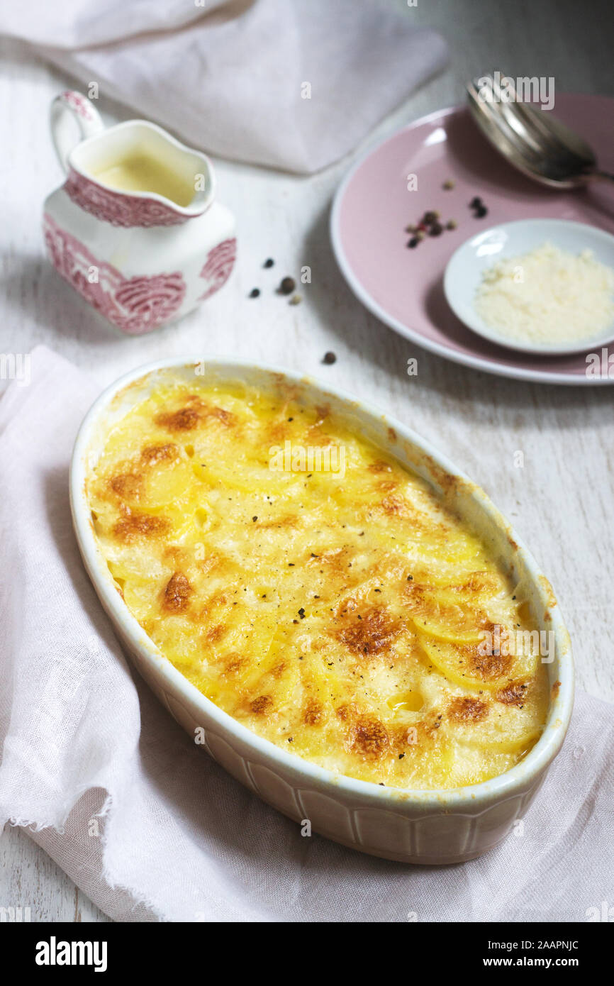 French dish Gratin Dauphinois in ceramic form on a light background. Rustic style. Stock Photo