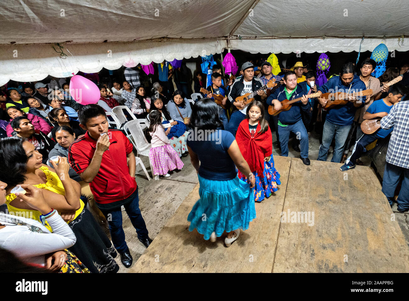 Zapateado dancers perform a traditional folk dance during a neighborhood Huapango in Santiago Tuxtla, Veracruz, Mexico. The dance involves dancers striking their shoes on a wooden platform while a large group of musicians play string instruments. The gatherings take part in the Los Tuxtlas mountain villages for single people to meet. Stock Photo