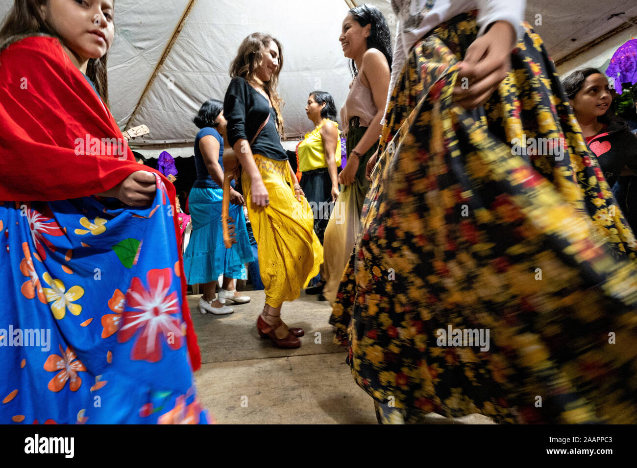 Zapateado dancers perform a traditional folk dance during a neighborhood Huapango in Santiago Tuxtla, Veracruz, Mexico. The dance involves dancers striking their shoes on a wooden platform while a large group of musicians play string instruments. The gatherings take part in the Los Tuxtlas mountain villages for single people to meet. Stock Photo