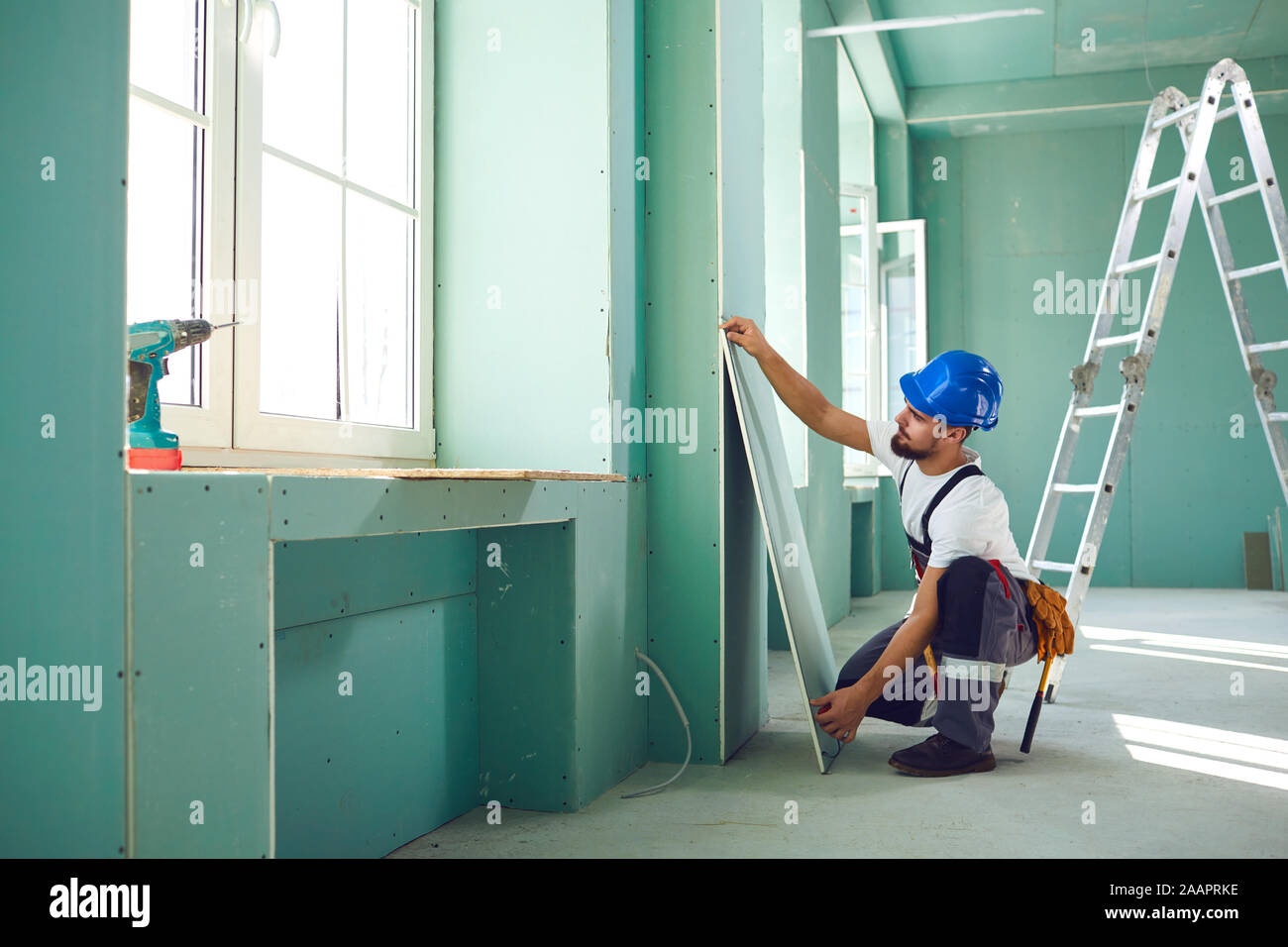 Worker builder installs plasterboard drywall at a construction Stock Photo