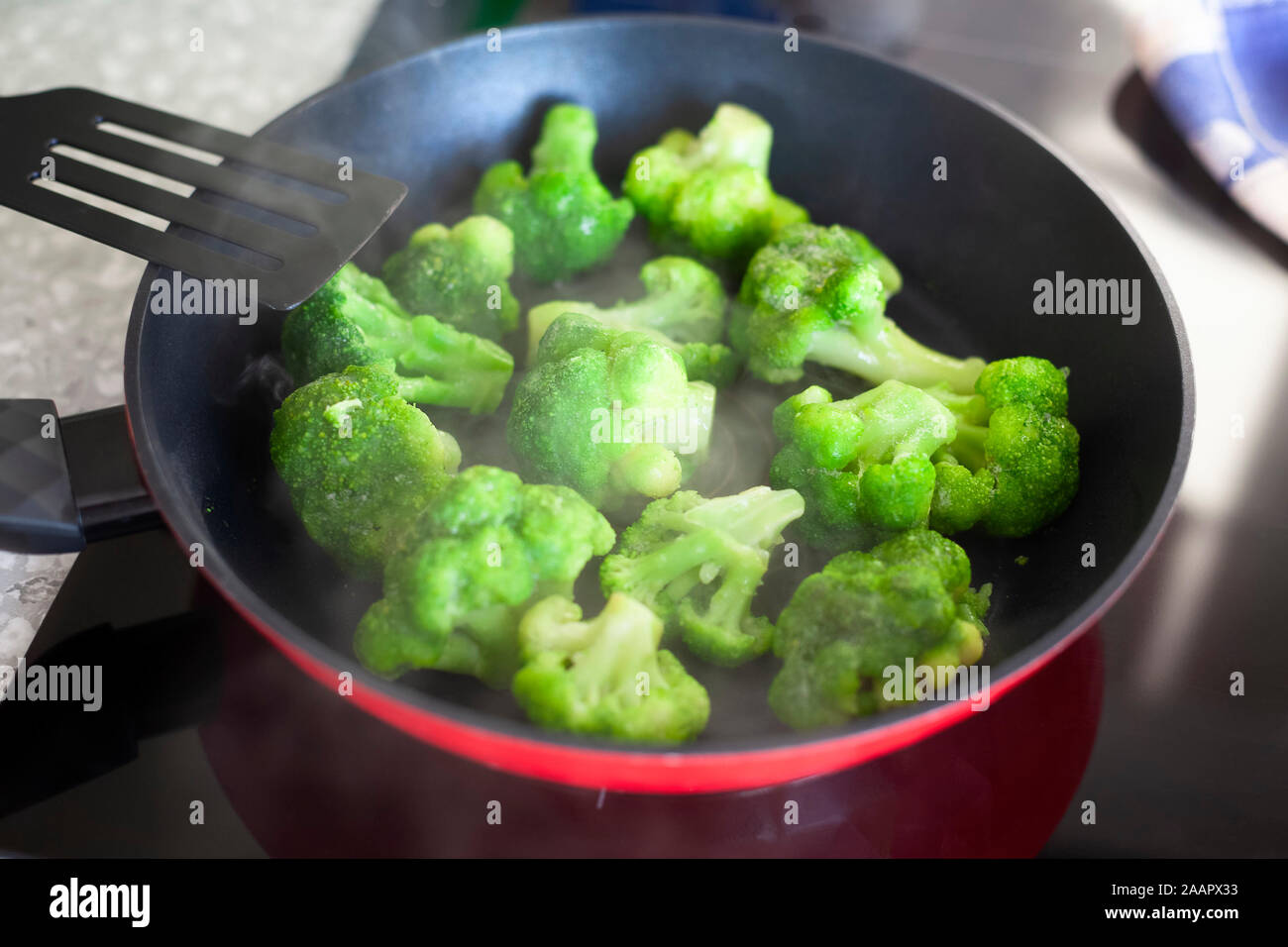 Frying frozen broccoli in a pan. Close up. Stock Photo
