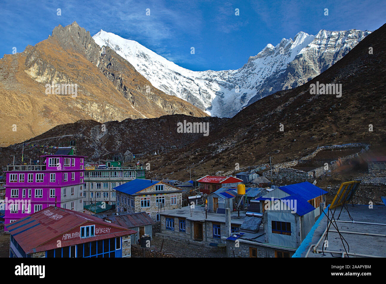 small village of Kyanjin Gompa in the shadow of the mountains with blue roofs and pink house Stock Photo