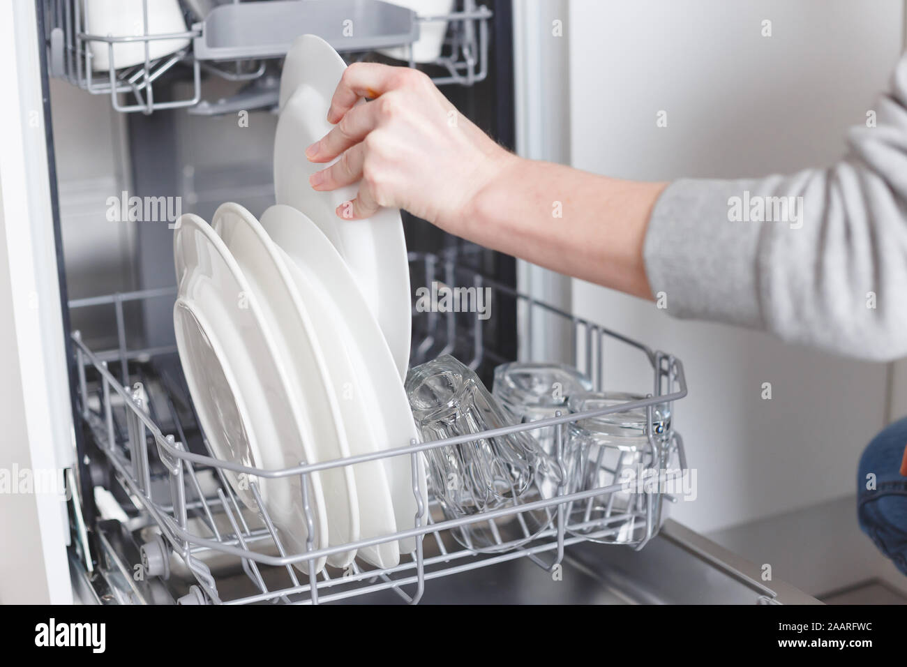 Housework young woman putting dishes in the dishwasher Stock Photo Alamy